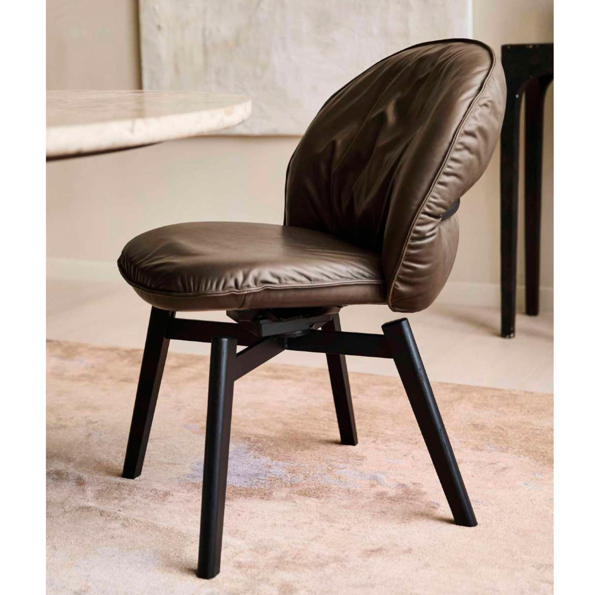 Marie Chair in olivbraunem Leder Adora Walnut mit schwarzer Holz-Kreuzzarge, im Raum an einem Tisch