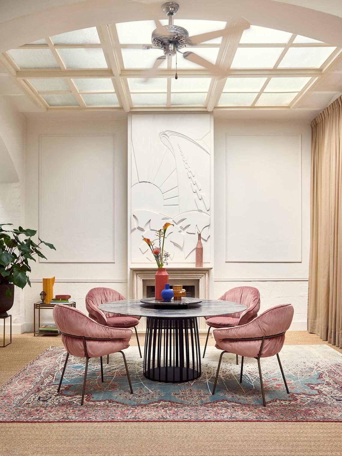 Vier Marie Armchairs in rosa Velours an einem runden Tisch in einem hellen Saal mit Oberlicht